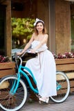 Mooie vrouw op een uitstekende fiets dichtbij de koffie van de de zomerstraat Stock Fotografie Mooie vrouw op een uitstekende fiets dichtbij de koffie van de de zomerstraat Stock Fotografie