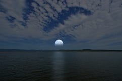 Mooie witte volle maan en wolken in blauwe hemel over het meer en de bergen royalty-vrije stock foto Mooie witte volle maan en wolken in blauwe hemel over het meer en de bergen royalty-vrije stock foto