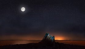 Moon and stars over stone in desert