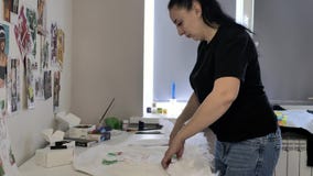 Morenita en una camiseta negra y los vaqueros que intentan en plumas a la chaqueta cerca de la ventana Morenita en una camiseta negra y los vaqueros que intentan en plumas a la chaqueta cerca de la ventana