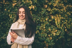 Morenita joven hermosa que se sienta en las hojas de un otoño caidas en un parque, leyendo un eBook en una tableta Imagenes de archivo Morenita joven hermosa que se sienta en las hojas de un otoño caidas en un parque, leyendo un eBook en una tableta Imagenes de archivo