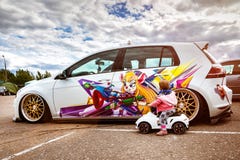 Moscow, Russia: July 06, 2019: Baby sits on a toy vehicle near tuned by low suspension and custom colored wheels. White volkswagen