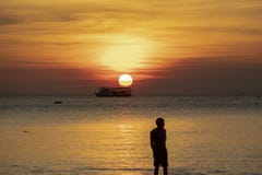 Mostre em silhueta a fotografia do homem na praia do mar contra o sol bonito Fotos de Stock Mostre em silhueta a fotografia do homem na praia do mar contra o sol bonito Fotos de Stock