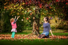 Mother And Girl Having Fun Under Tree With Autumn Leaves In The Park, Blond Cute Curly Girl, Happy And Young Family Royalty Free Stock Photos Mother And Girl Having Fun Under Tree With Autumn Leaves In The Park, Blond Cute Curly Girl, Happy And Young Family Royalty Free Stock Photos