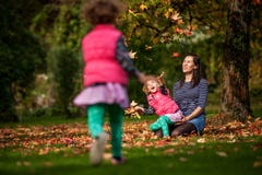 Mother And Identical Twins Having Fun With Autumn Leaves In The Park, Blond Cute Curly Girls, Happy Kids, Girls In Pink Jacket Stock Photos