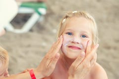 Mother applying sunscreen protection creme on cute little daughter face. Mom using sunblocking lotion to protect kid girl from sun royalty free stock photos Mother applying sunscreen protection creme on cute little daughter face. Mom using sunblocking lotion to protect kid girl from sun royalty free stock photos