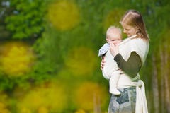 Mother Carrying Daughter In Sling In Park Stock Photography