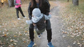 Mother circling a little son in an autumn park. Happy family in autumn park. Happy family in nature concept in slow stock video footage Mother circling a little son in an autumn park. Happy family in autumn park. Happy family in nature concept in slow stock video footage