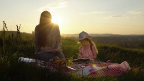 Mother And Daughter Drawing On A Picnic On A Hill In The Summer At