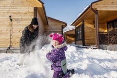 Mother and daughter happy, active play in the snowy yard of his