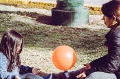 Mother and daughter playing ball on the grass in the park. stock photo Mother and daughter playing ball on the grass in the park. stock photo