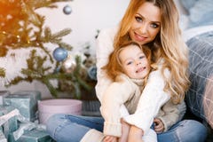 Mother and daughter sitting by the christmas tree. Mother hugging daughter and sitting by the christmas tree Stock Photography Mother and daughter sitting by the christmas tree. Mother hugging daughter and sitting by the christmas tree Stock Photography