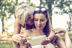 Mother and daughter in swimsuit having fun watching a digital tablet stock image Mother and daughter in swimsuit having fun watching a digital tablet stock image