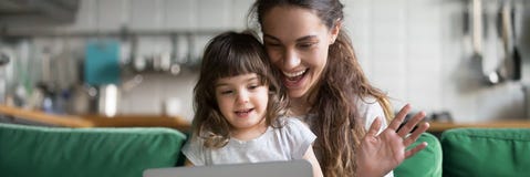 Mother and daughter waving hands looking at camera using computer stock image Mother and daughter waving hands looking at camera using computer stock image
