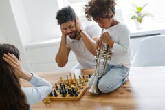 Mother and father trying to play chess while their child plays trumpet Royalty Free Stock Photography Mother and father trying to play chess while their child plays trumpet Royalty Free Stock Photography