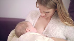 Mother feeding baby at home. Mom breast feeding toddler. Mother care concept