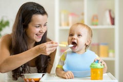 Mother feeding her baby with spoon. Mother giving healthy food to her adorable child at home royalty free stock image Mother feeding her baby with spoon. Mother giving healthy food to her adorable child at home royalty free stock image