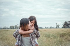 Mother giving daughter ride on back in park. royalty free stock photos Mother giving daughter ride on back in park. royalty free stock photos