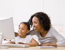 Mother helping girl do homework on computer
