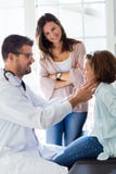 Mother with her daughter having throat examination by pediatrician in the office. Royalty Free Stock Photography Mother with her daughter having throat examination by pediatrician in the office. Royalty Free Stock Photography