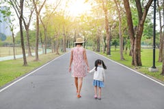 Mother and her daughter walking on the road and holding hands in the outdoor nature garden. Back view royalty free stock image Mother and her daughter walking on the road and holding hands in the outdoor nature garden. Back view royalty free stock image