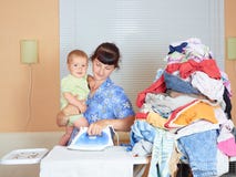 Mother holding baby in arm, ironing with the other arm. stock photos Mother holding baby in arm, ironing with the other arm. stock photos