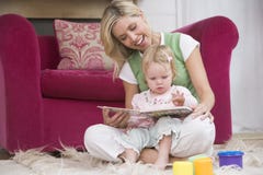 Mother in living room reading book with baby