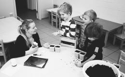 Mother and Three Child Near Table With Mud stock photos Mother and Three Child Near Table With Mud stock photos