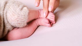 Hand touching little newborn small feets