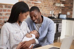 Mother Working On Laptop Holds Newborn Son With Father royalty free stock photo Mother Working On Laptop Holds Newborn Son With Father royalty free stock photo