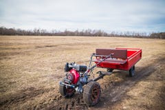 Motoblock con un rimorchio che va su una strada del campo in primavera a marzo, la nuova stagione del lavoro di campo immagini stock libere da diritti Motoblock con un rimorchio che va su una strada del campo in primavera a marzo, la nuova stagione del lavoro di campo immagini stock libere da diritti
