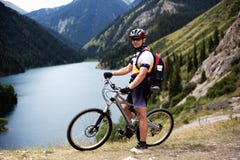 Motociclista ao lado do lago da montanha imagem de stock Motociclista ao lado do lago da montanha imagem de stock