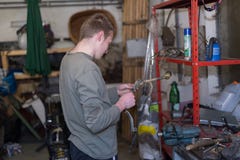Motor die door de knappe jonge mens in zijn garagerand herstellen stock foto's Motor die door de knappe jonge mens in zijn garagerand herstellen stock foto's