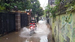 20 February 2021, Motorcyle acrossing Flooding small street at Condet East Jakarta, Indonesia