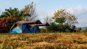 Motorfiets op bruin gras naast tent, beschikbare ruimte wordt geparkeerd die camping royalty-vrije stock foto's Motorfiets op bruin gras naast tent, beschikbare ruimte wordt geparkeerd die camping royalty-vrije stock foto's