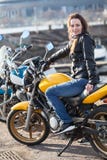 Motorista de la mujer joven que se sienta en su bici de la calle y que mira la cámara Imágenes de archivo libres de regalías Motorista de la mujer joven que se sienta en su bici de la calle y que mira la cámara Imágenes de archivo libres de regalías