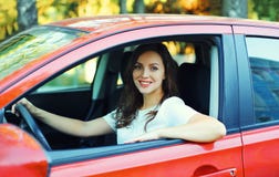Motorista de sorriso feliz da mulher atrás do carro do vermelho da roda fotos de stock Motorista de sorriso feliz da mulher atrás do carro do vermelho da roda fotos de stock