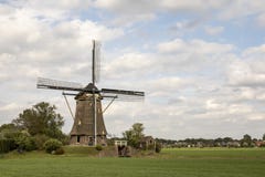 Moulin à vent néerlandais traditionnel dans la campagne aux Pays-Bas entourée par le pâturage sous un ciel nuageux photographie stock Moulin à vent néerlandais traditionnel dans la campagne aux Pays-Bas entourée par le pâturage sous un ciel nuageux photographie stock