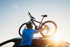 Mountain biker man takes of his bike from the car roof royalty free stock photography Mountain biker man takes of his bike from the car roof royalty free stock photography
