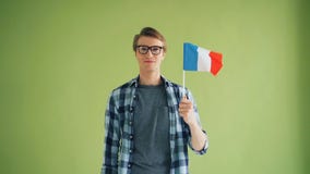Mouvement lent de type beau avec le drapeau fran?ais regardant la cam?ra et le sourire banque de vidéos Mouvement lent de type beau avec le drapeau fran?ais regardant la cam?ra et le sourire banque de vidéos