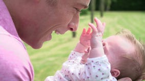 Mouvement lent tiré du père Holding Baby Daughter dans le jardin banque de vidéos Mouvement lent tiré du père Holding Baby Daughter dans le jardin banque de vidéos