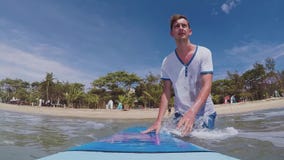 Movimento lento: il giovane surfista cammina nell'oceano con un surf Movimento lento: il giovane surfista cammina nell'oceano con un surf