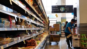 Movimiento de la comida de la media del trabajador en el estante de exhibición dentro de la tienda de comidas elegante del precio Movimiento de la comida de la media del trabajador en el estante de exhibición dentro de la tienda de comidas elegante del precio