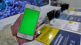 Movimiento de la mujer que celebra el teléfono de pantalla verde delante de la cámara digital de la exhibición en venta Movimiento de la mujer que celebra el teléfono de pantalla verde delante de la cámara digital de la exhibición en venta