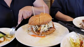 Movimiento de la mujer que come la hamburguesa en el restaurante chino almacen de video Movimiento de la mujer que come la hamburguesa en el restaurante chino almacen de video