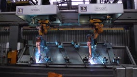 Movimiento de los robots de soldadura en fábrica del coche escena Movimiento del robot al soldar con autógena con las chispas en almacen de video Movimiento de los robots de soldadura en fábrica del coche escena Movimiento del robot al soldar con autógena con las chispas en almacen de video