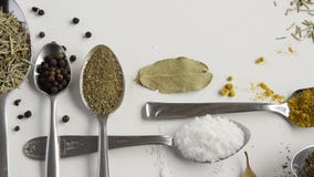 Movimientos de la cámara adelante de cucharas con las diversas hierbas y especias aromáticas en el fondo blanco Movimientos de la cámara adelante de cucharas con las diversas hierbas y especias aromáticas en el fondo blanco