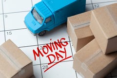Moving Day On The Calendar Is Written In Red. Calendar With A Note With Cardboard Boxes And Truck. Stock Photo Moving Day On The Calendar Is Written In Red. Calendar With A Note With Cardboard Boxes And Truck. Stock Photo
