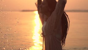 A moça atrativa faz o espirro de suas mãos que estão na água na perspectiva do sol Movimento lento video estoque A moça atrativa faz o espirro de suas mãos que estão na água na perspectiva do sol Movimento lento video estoque