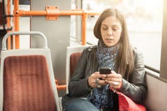 A moça usa um telefone celular no ônibus da cidade imagem de stock A moça usa um telefone celular no ônibus da cidade imagem de stock